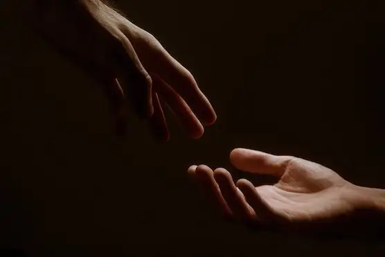 Hands reaching toward each other in the dark